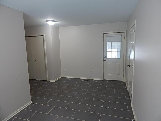 entryway with baseboards and dark tile patterned floors