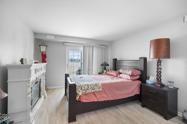 3553 Port Cove Dr Unit 37, Waterford, MI 48328 - bedroom with baseboards, light wood-type flooring, and a glass covered fireplace