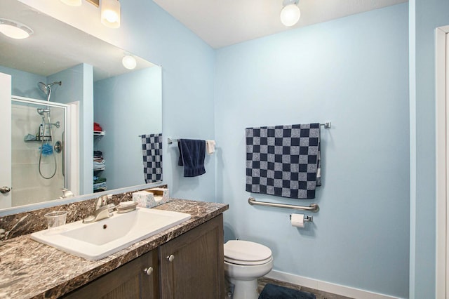 full bathroom featuring baseboards, vanity, a shower with door, and toilet