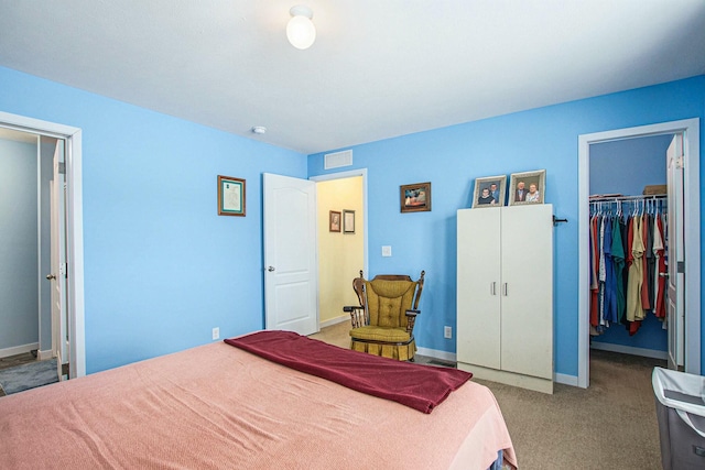 bedroom featuring carpet flooring, baseboards, visible vents, a closet, and a walk in closet
