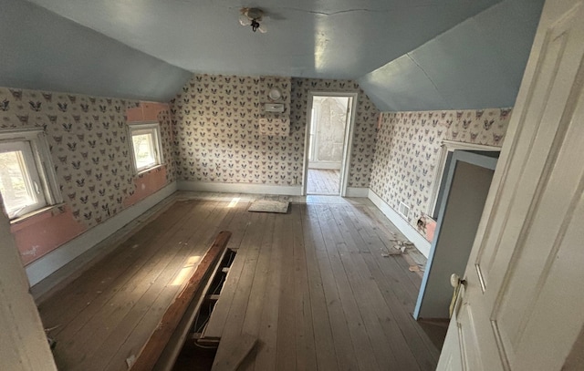 additional living space with hardwood / wood-style floors, wallpapered walls, lofted ceiling, and baseboards