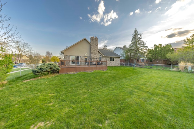 rear view of house featuring a fenced backyard, a chimney, a yard, and a deck