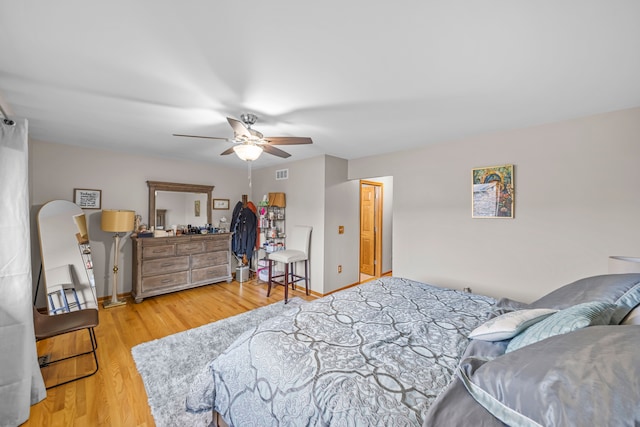 bedroom with baseboards, ceiling fan, wood finished floors, and visible vents