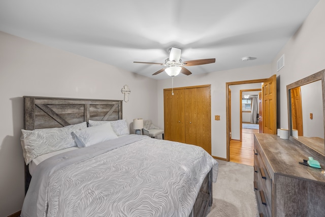bedroom with visible vents, a ceiling fan, light carpet, and a closet