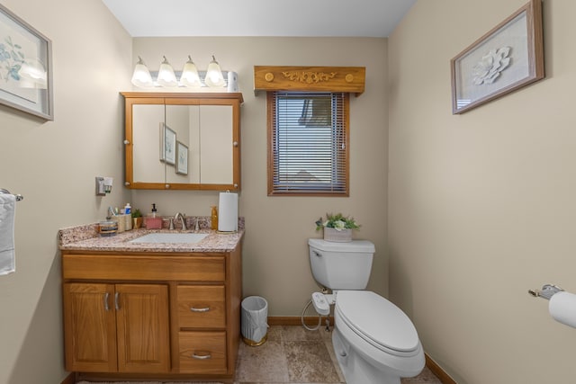 bathroom with baseboards, toilet, and vanity