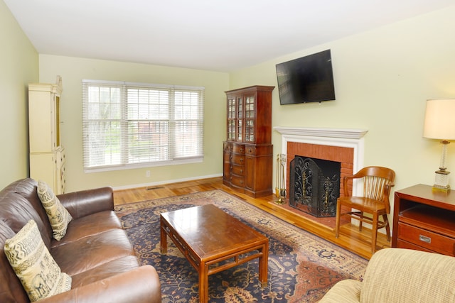 living area with wood finished floors, a fireplace, and baseboards