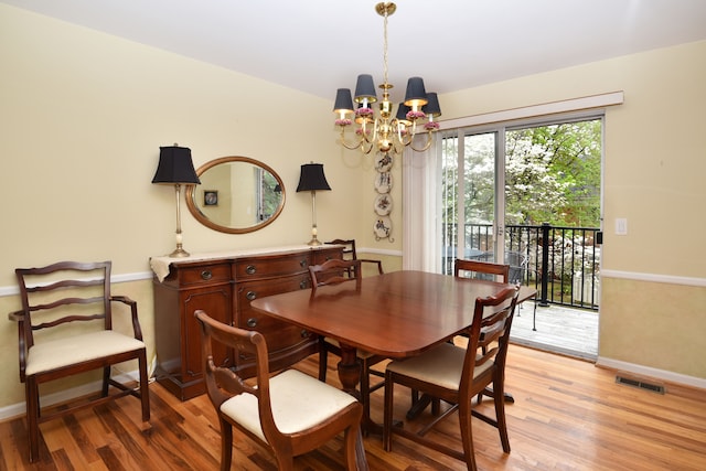 dining area featuring a chandelier, light wood finished floors, and baseboards