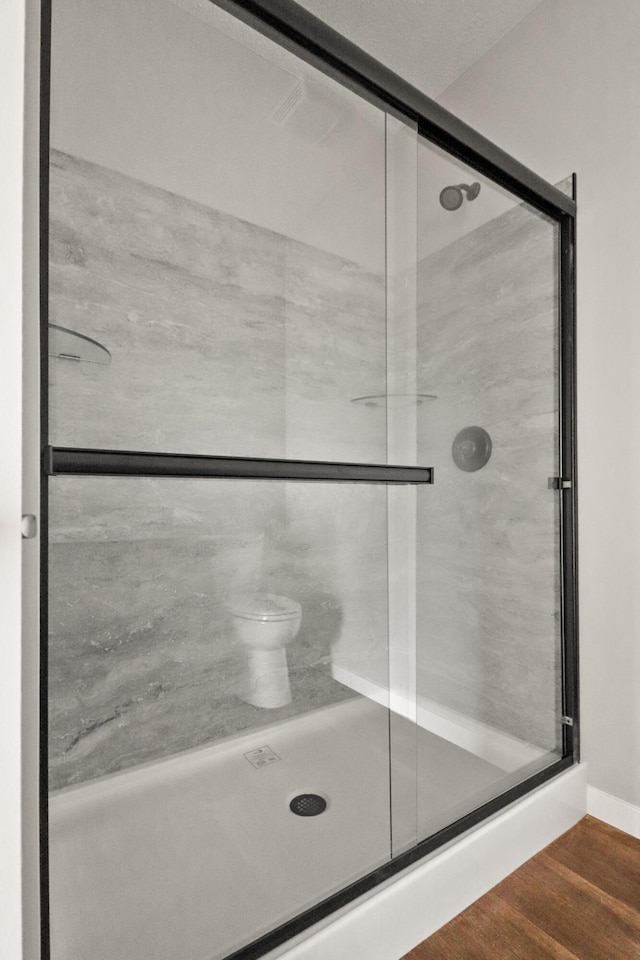 10820 Baker Rd, Jerome, MI 49249 - bathroom featuring a stall shower, wood finished floors, and toilet