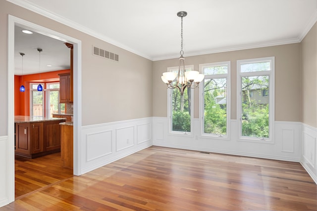 24160 Argyle St, Novi, MI 48374 - unfurnished dining area featuring light wood finished floors, wainscoting, a chandelier, a decorative wall, and crown molding