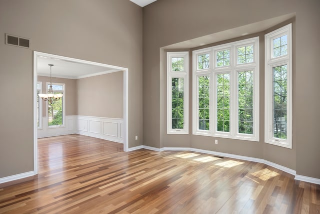 24160 Argyle St, Novi, MI 48374 - empty room with a chandelier, wood finished floors, ornamental molding, a towering ceiling, and baseboards
