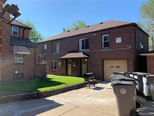 view of front of house with concrete driveway, brick siding, a front yard, and a garage