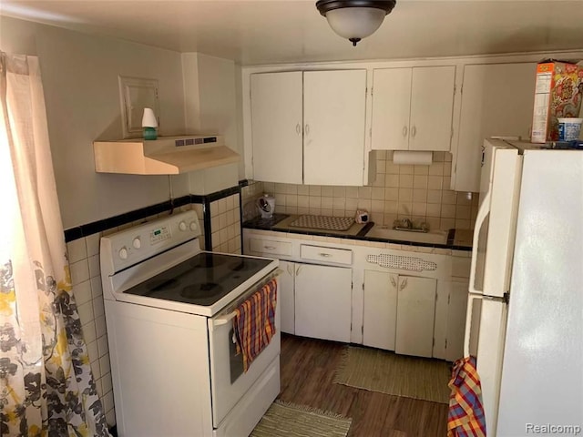 kitchen featuring white cabinetry, under cabinet range hood, dark wood-type flooring, and white appliances