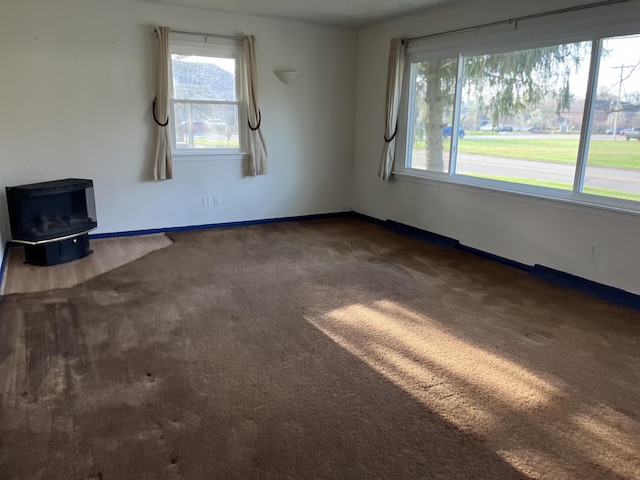 2120 Hemlock Ave, Portage, MI 49024 - unfurnished living room with a wood stove, carpet floors, and baseboards