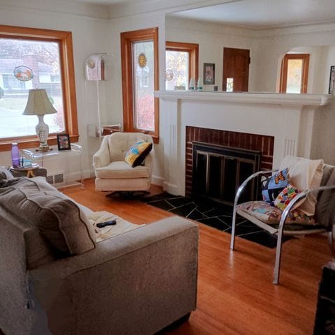 living room featuring a fireplace, wood finished floors, a healthy amount of sunlight, and baseboards