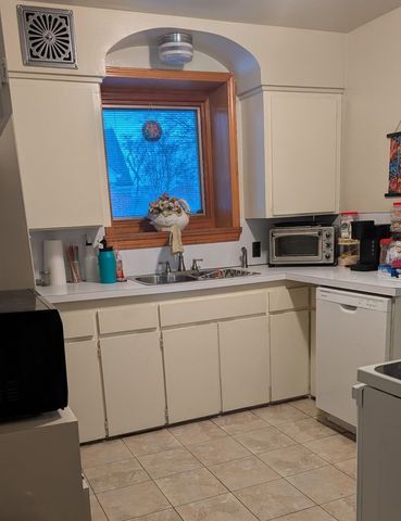 kitchen with stainless steel microwave, white dishwasher, a sink, and light countertops