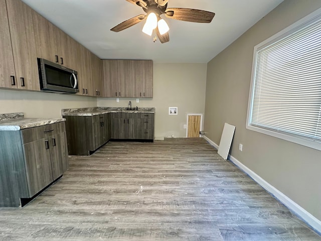 kitchen with stainless steel microwave, a ceiling fan, a sink, and light wood-style floors