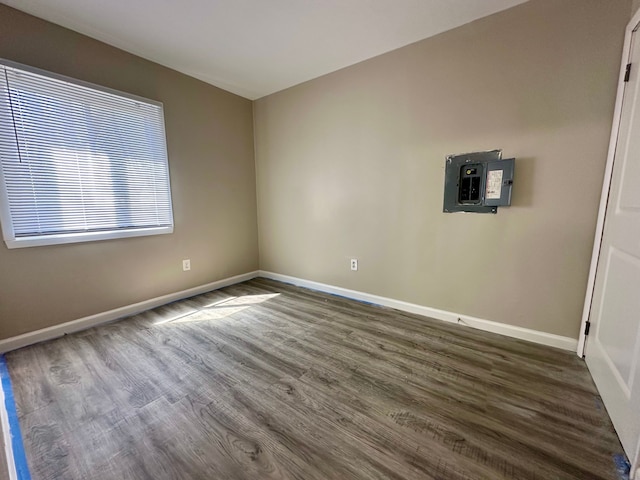 unfurnished room featuring dark wood-style floors, baseboards, and electric panel