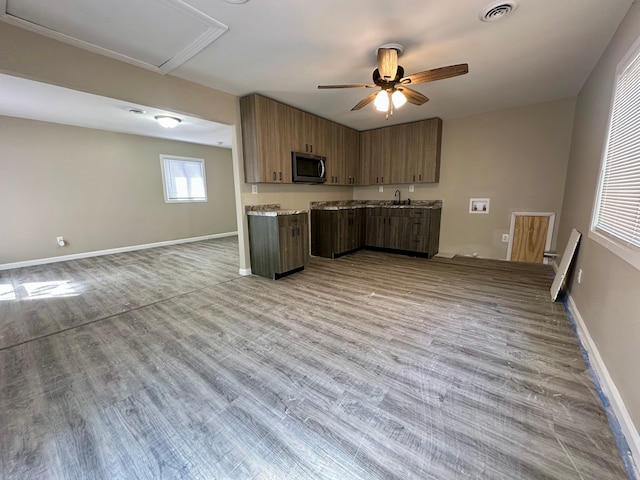 kitchen featuring stainless steel microwave, ceiling fan, visible vents, baseboards, and open floor plan