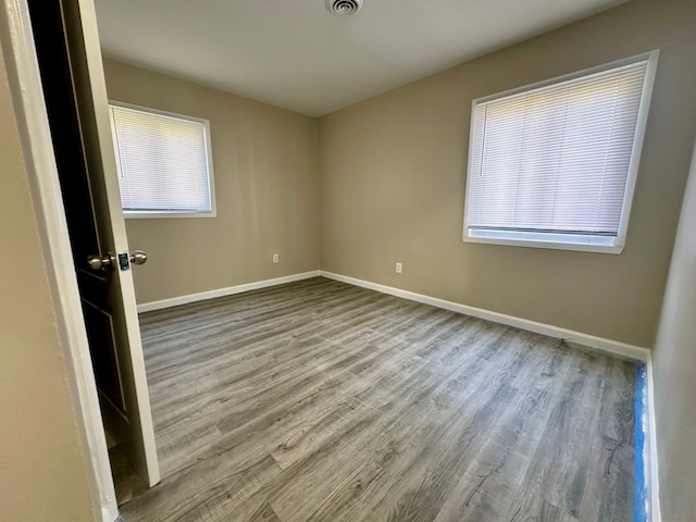 spare room featuring baseboards, visible vents, and wood finished floors