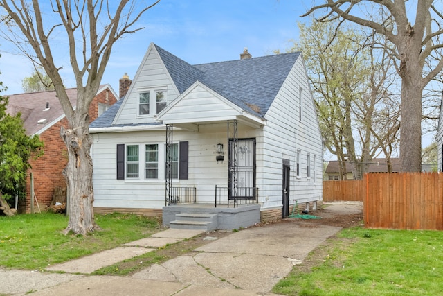 view of front of home with fence, a chimney, a shingled roof, and a front yard
