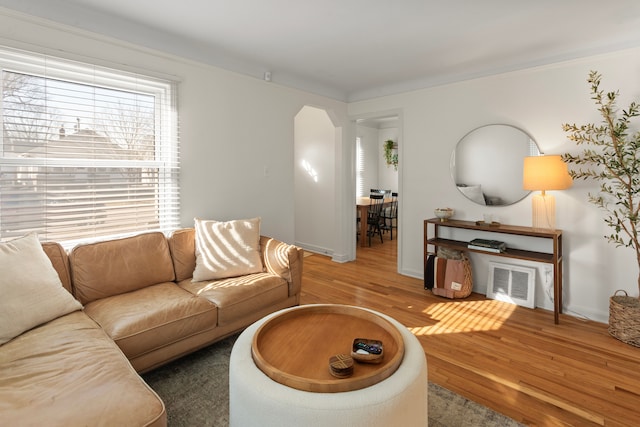 living area with baseboards, arched walkways, wood finished floors, and visible vents