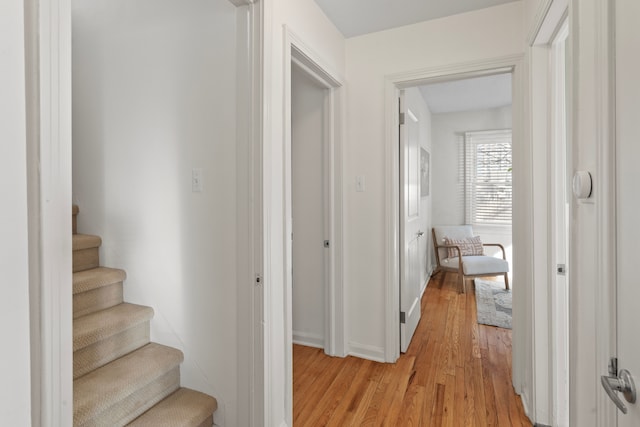 corridor featuring stairway, baseboards, and light wood-type flooring
