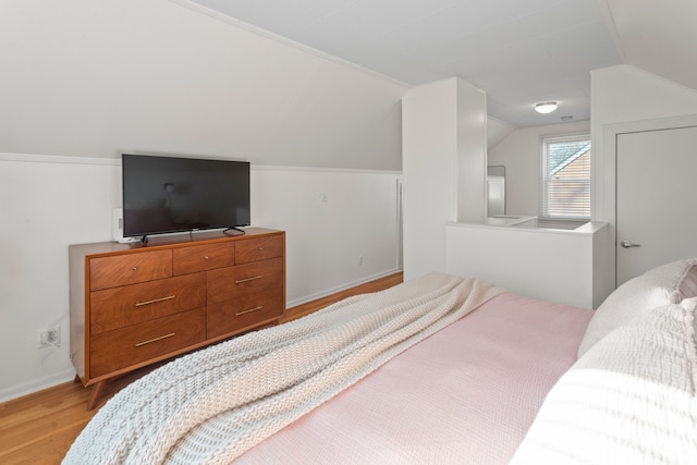bedroom featuring baseboards, vaulted ceiling, and light wood finished floors