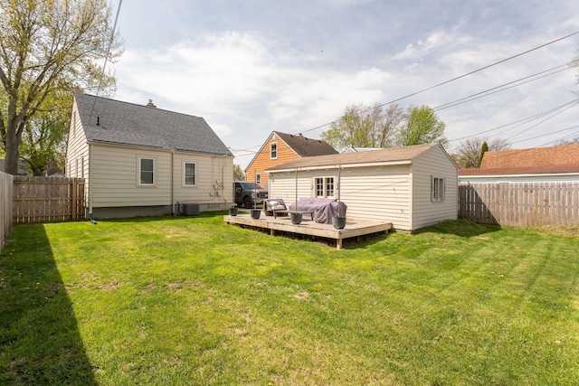 back of property with a fenced backyard, a yard, a deck, and central AC unit