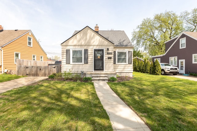 view of front of house with roof with shingles, fence, a front yard, and a chimney