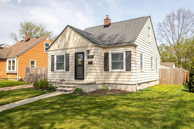 view of front of house with a shingled roof, fence, a front yard, and a chimney