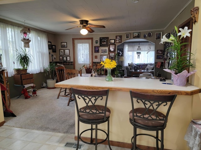 927 George St S, Jackson, MI 49202 - kitchen with ceiling fan, light floors, ornamental molding, open floor plan, and a breakfast bar area