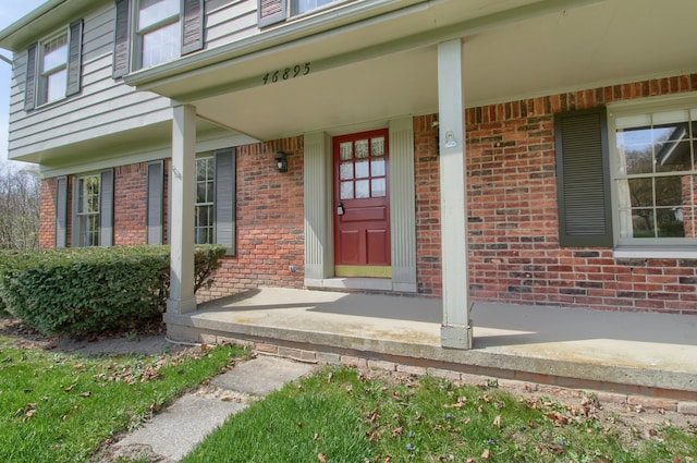 doorway to property featuring covered porch and brick siding
