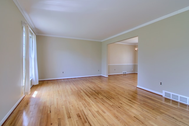unfurnished room with baseboards, visible vents, light wood-type flooring, and crown molding