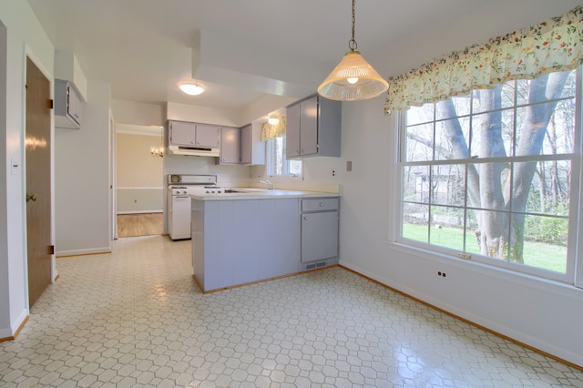 kitchen featuring under cabinet range hood, gray cabinets, a peninsula, baseboards, and white range