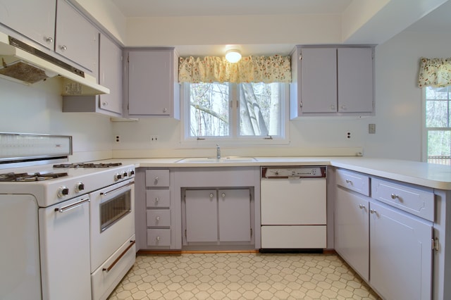 kitchen with gray cabinetry, white appliances, under cabinet range hood, and a sink