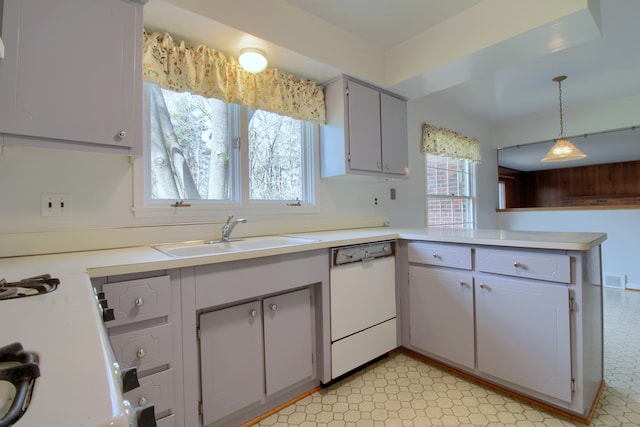 kitchen featuring a peninsula, light countertops, white dishwasher, and a sink