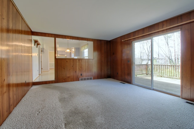 spare room featuring visible vents, wood walls, and carpet