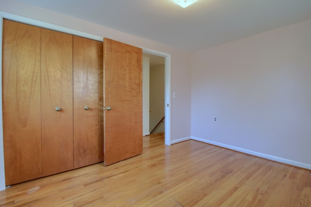 unfurnished bedroom with a closet, baseboards, and light wood-type flooring