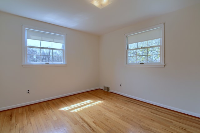 spare room with visible vents, wood-type flooring, and baseboards