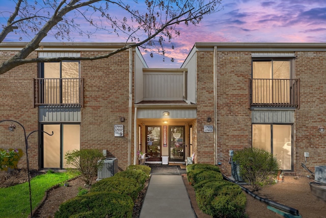 view of front facade with central AC unit and brick siding