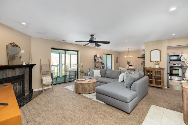carpeted living room with ceiling fan with notable chandelier, a tile fireplace, baseboards, and recessed lighting