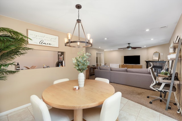 dining room with ceiling fan with notable chandelier, light carpet, visible vents, and light tile patterned floors