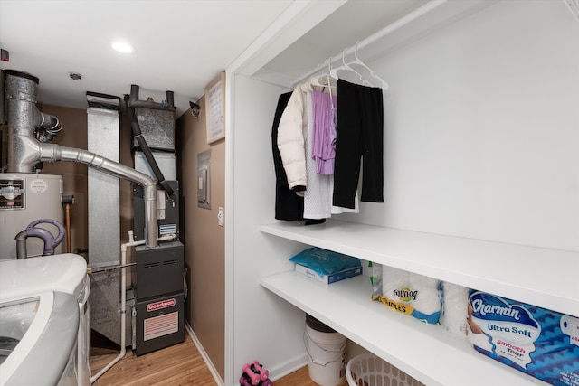 spacious closet featuring water heater and light wood-style flooring