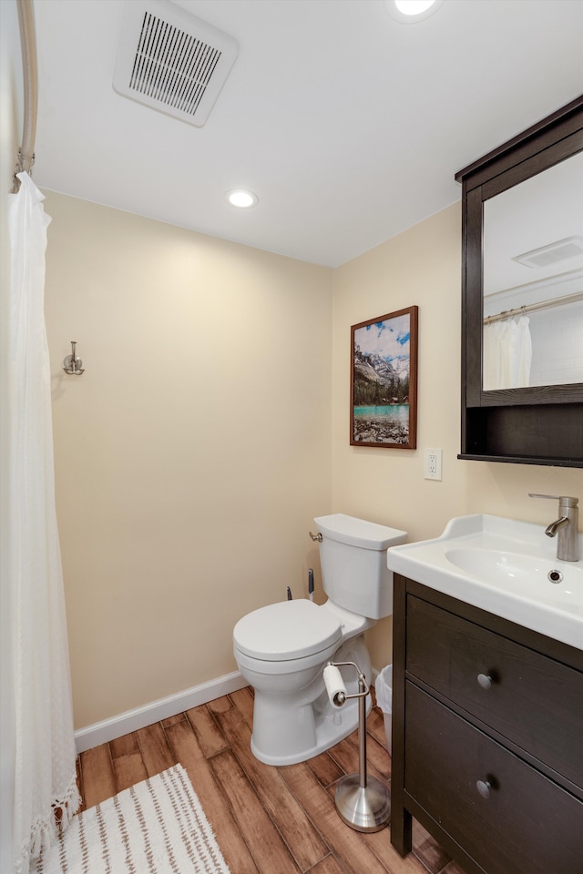 full bath featuring toilet, baseboards, visible vents, wood finished floors, and vanity