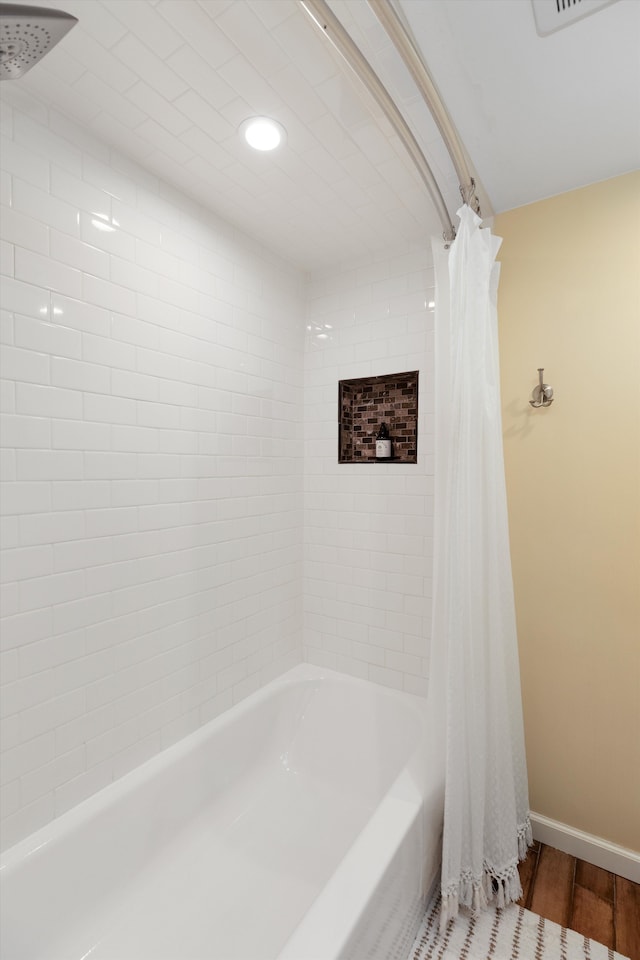 bathroom featuring shower / bath combination with curtain, baseboards, wood finished floors, and recessed lighting