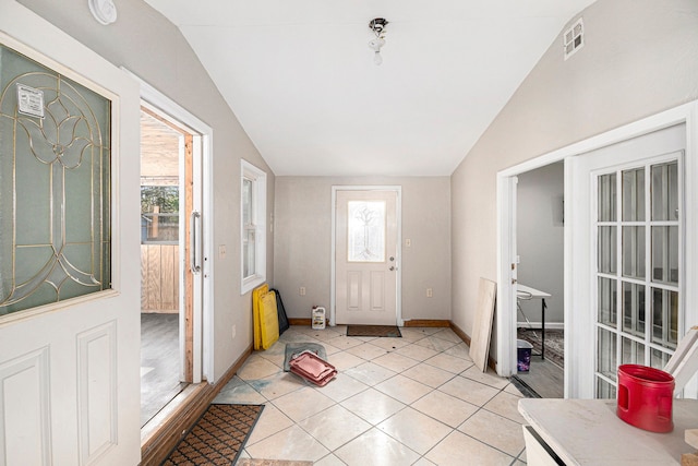 foyer featuring visible vents, light tile patterned flooring, vaulted ceiling, and a wealth of natural light