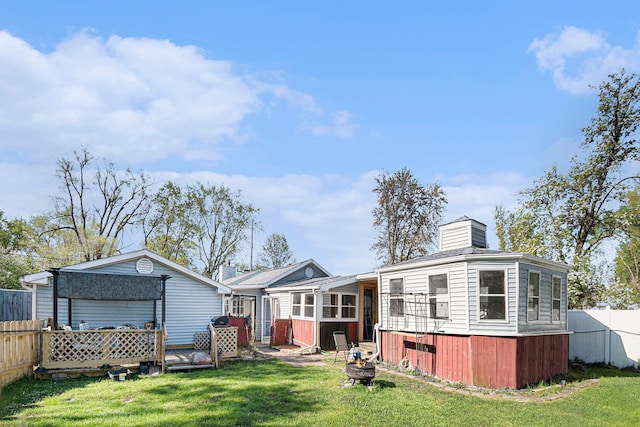 rear view of property with fence, a chimney, a yard, and an outdoor fire pit