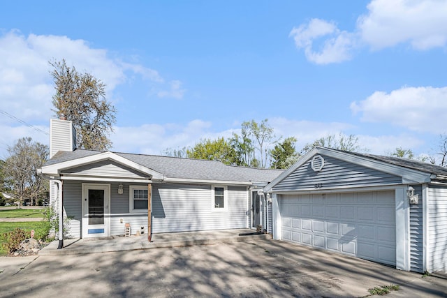 ranch-style home with a garage, a chimney, concrete driveway, and a porch