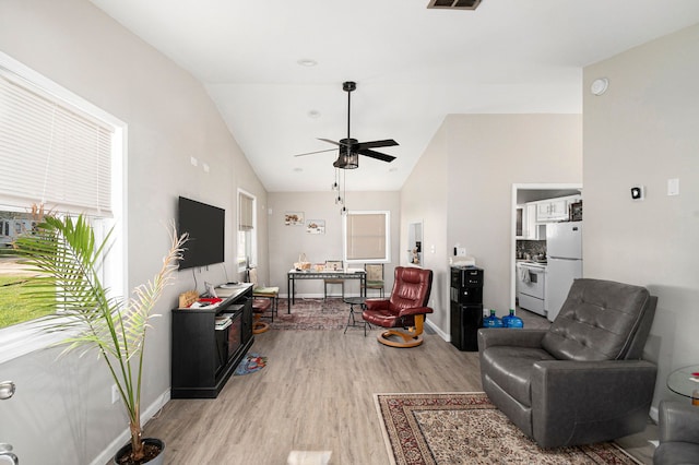 living area with ceiling fan, lofted ceiling, baseboards, and light wood finished floors