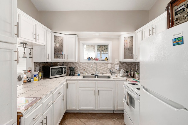 kitchen with white appliances, white cabinets, a sink, and tasteful backsplash